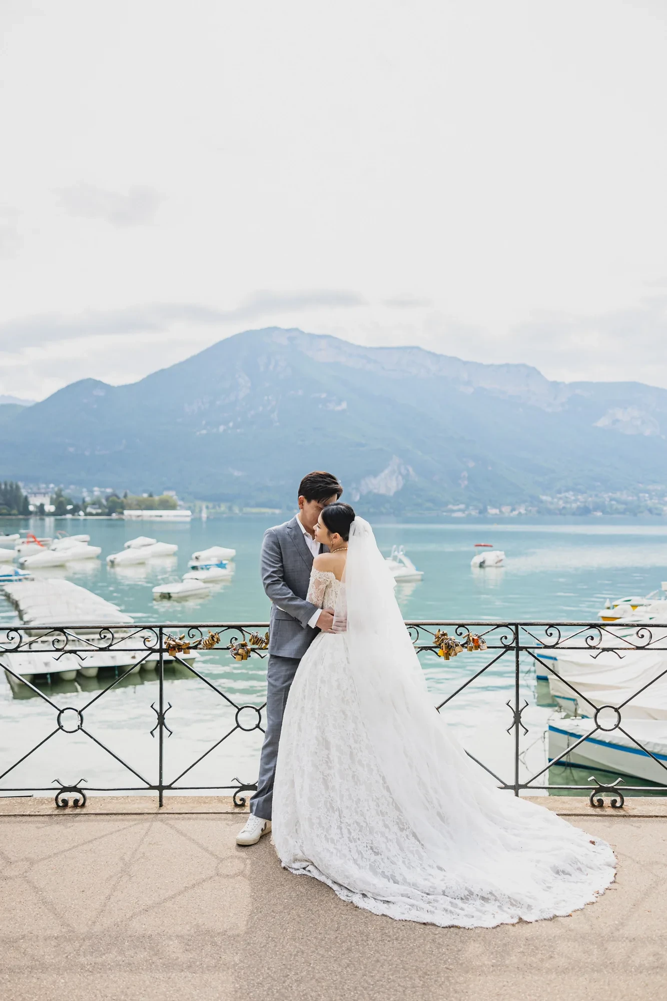 newlyweds-lake-mountains-veil-train.webp