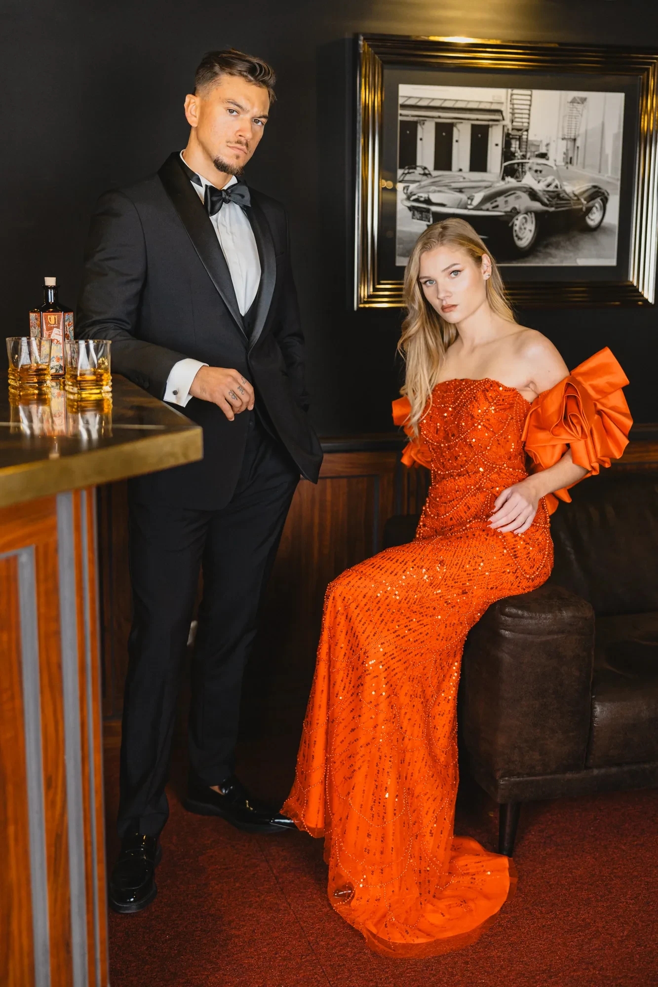 glamour-couple-tuxedo-orange-dress-bar.webp