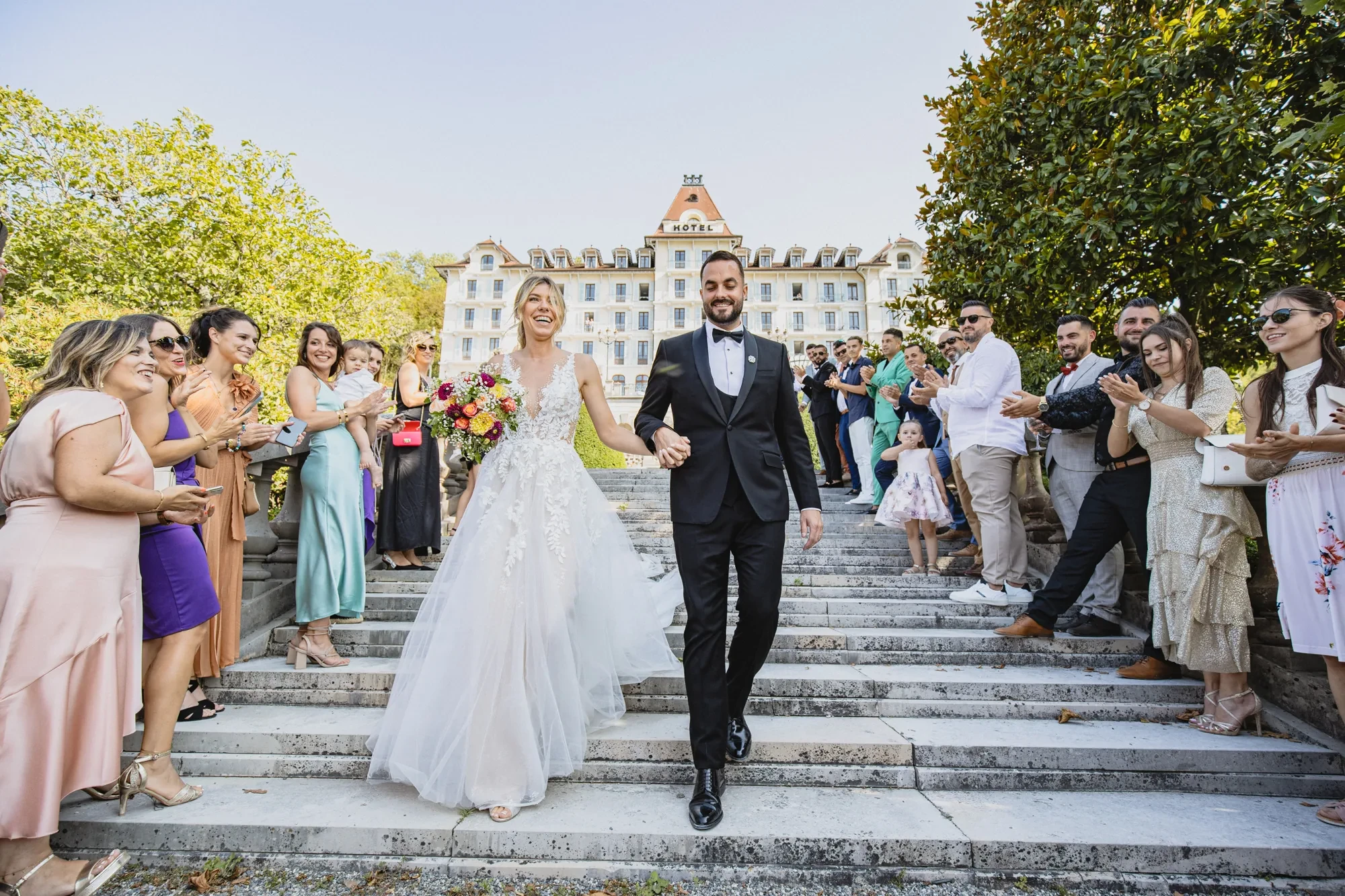 newlyweds-exit-staircase-applause-hotel.webp newlyweds-exit-staircase-applause-hotel.webp