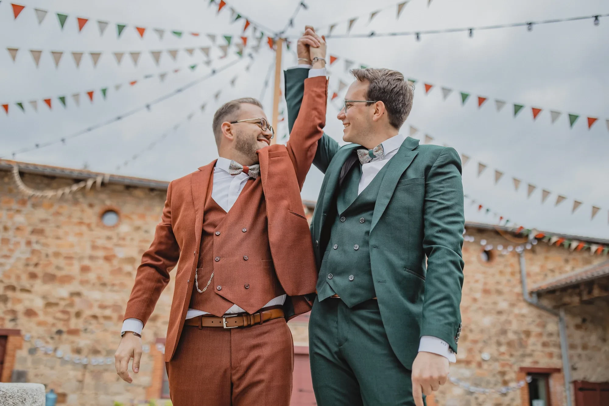 two-grooms-suits-bunting-courtyard.webp