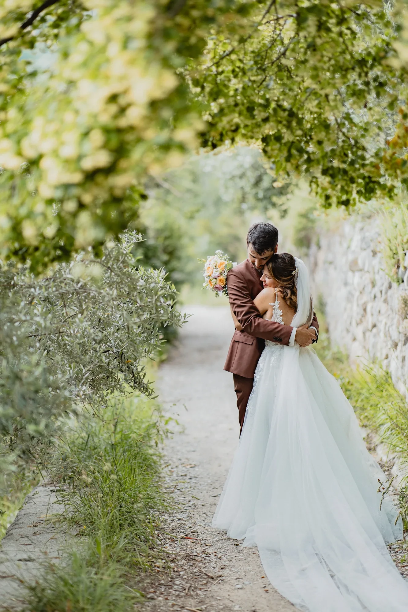 newlyweds-embrace-olive-grove-path.webp newlyweds-embrace-olive-grove-path.webp