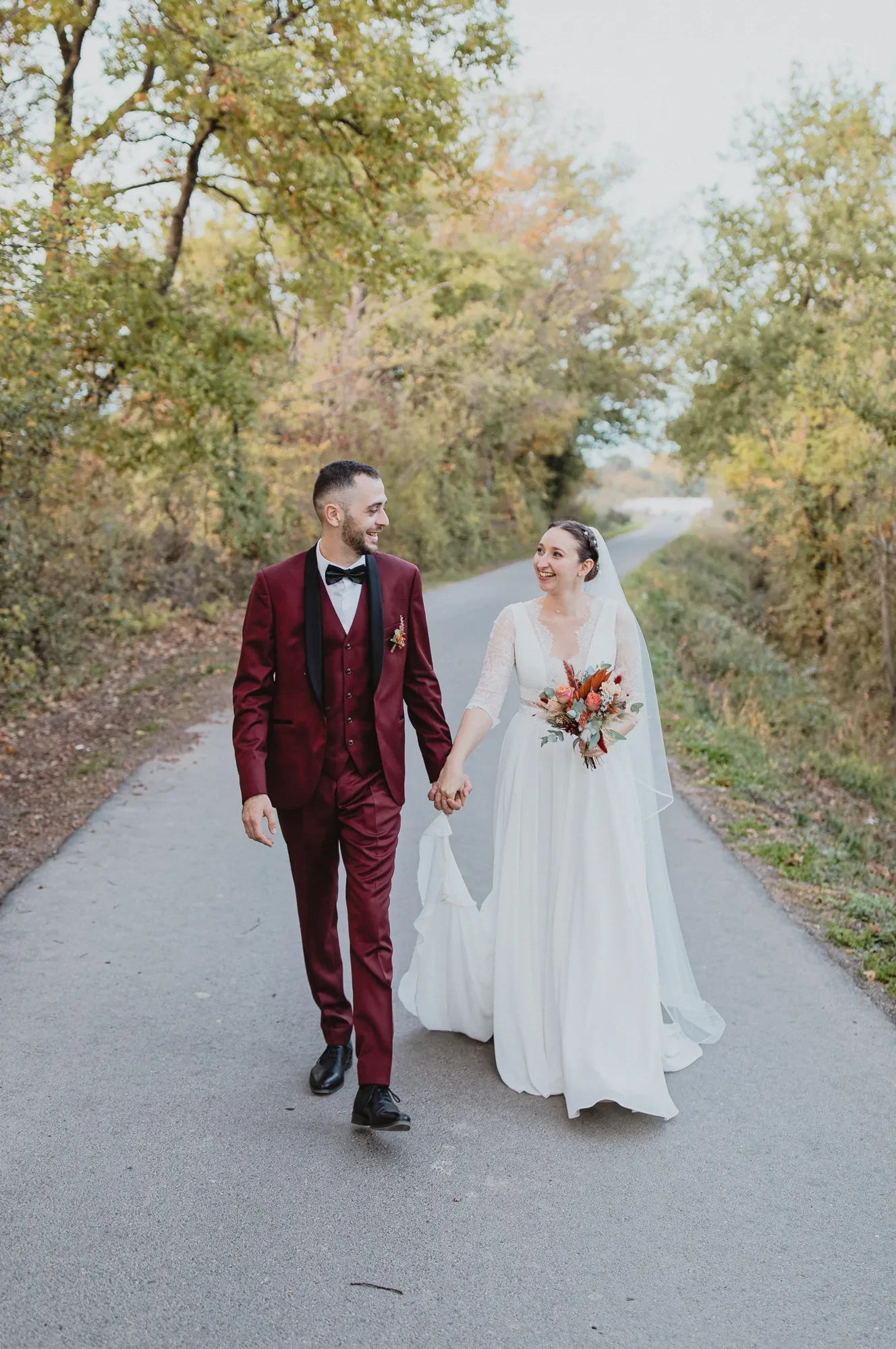 newlyweds-walking-autumn-path.webp